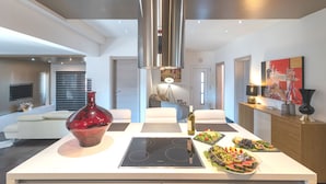 A modern kitchen with a central island, a large red vase, and a dining area with a sofa and a lamp.