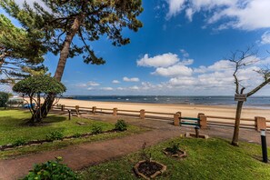 A beach view with a wooden fence, a sign reading 'PELOUSE INTERDITE,' and a paved walkway. - Apartment “Eugénie” with Arcachon Bay View, Private Terrace, Beach Access, and Wi-Fi (Arcachon)