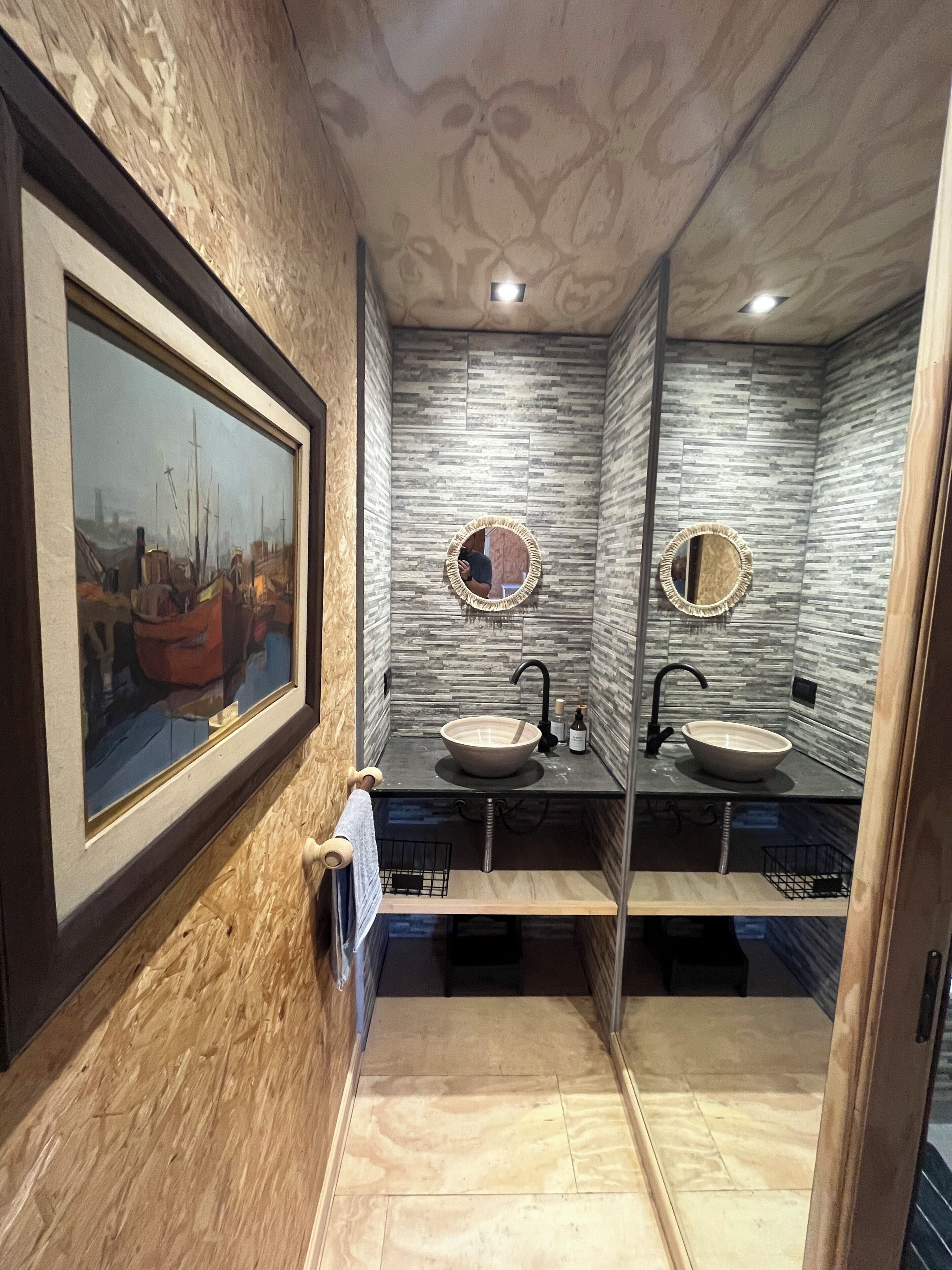 A bathroom with two sinks, a framed painting, and a mirror.