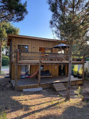 Eine Holzhütte mit Balkon, Hängematte und einer Terrasse.