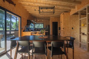 Une cuisine moderne avec des meubles en bois, un grand îlot central et un coin repas comprenant une table et des chaises noires.