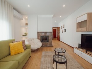 A modern living room with a sofa, a glass coffee table, a fireplace, and a TV. - CITY CENTER GRAND SEA VIEW TERRACE by VACATIONY by Interhome (Porto)