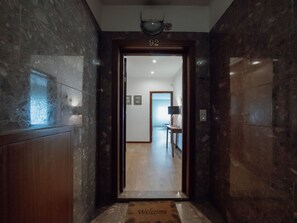 Un couloir au sol de marbre menant à une porte portant le numéro 92.