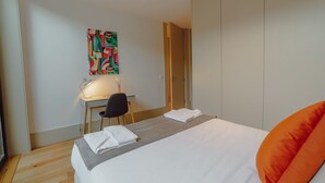 A hotel room with a bed, a desk, a chair, and a colorful abstract painting on the wall. - LEGACY OPORTO PREMIUM APARTMENT B by VACATIONY by Interhome (Porto)