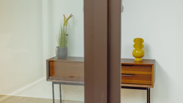 A corner of a room with a wooden console table, a potted plant, and a yellow decorative object. - LEGACY OPORTO PREMIUM APARTMENT B by VACATIONY by Interhome (Porto)