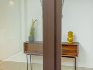 A corner of a room with a wooden console table, a potted plant, and a yellow decorative object. - LEGACY OPORTO PREMIUM APARTMENT B by VACATIONY by Interhome (Porto)