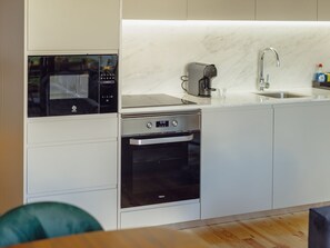 A modern kitchen with a built-in oven, a coffee machine, and a sink. - LEGACY OPORTO PREMIUM APARTMENT B by VACATIONY by Interhome (Porto)
