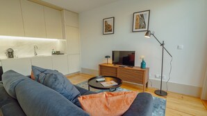 A modern living room with a sofa, coffee table, and a TV on a wooden cabinet. - LEGACY OPORTO PREMIUM APARTMENT B by VACATIONY by Interhome (Porto)