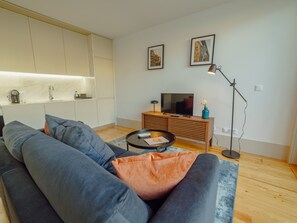 Ein modernes Wohnzimmer mit einer Couch, einem Couchtisch und einem Fernseher auf einer Holzkommode.