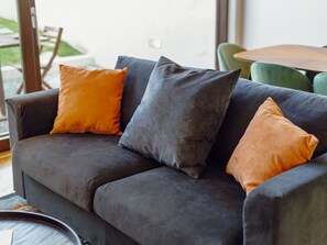 A dark grey sofa with three cushions in shades of orange and grey. - LEGACY OPORTO PREMIUM APARTMENT B by VACATIONY by Interhome (Porto)