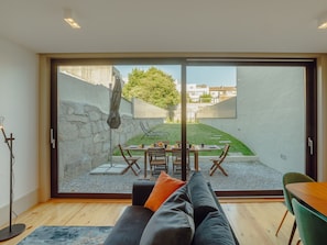 Uma sala de estar moderna com uma porta de vidro deslizante que dá para um quintal com área de jantar e móveis de exterior.