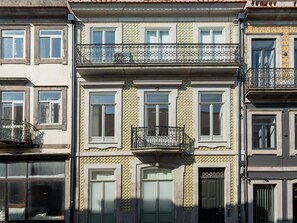 Um edifício com vários andares, varandas, janelas e uma porta.