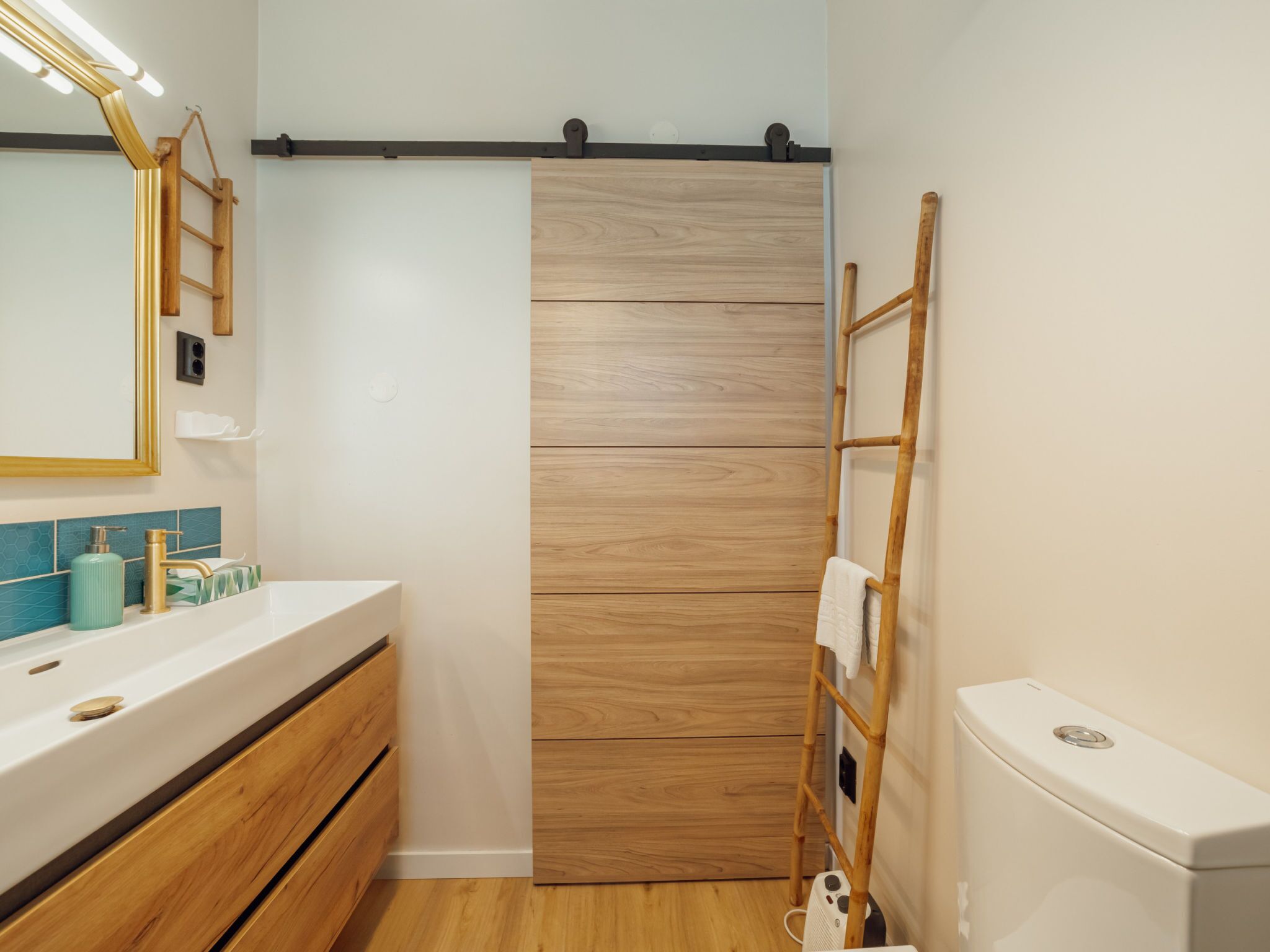 Ein modernes Badezimmer mit einem Holzlagerfläschchen, einem Spiegel, einem Handtuchhalter und einer Toilette.
