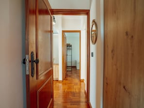 A hallway with wooden doors, a mirror on the wall, and a laundry area in the distance. - CASA DAS ORQUIDEAS by VACATIONY by Interhome (Porto)