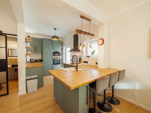 A modern kitchen with a central island, built-in appliances, and a dining area with bar stools. - CASA DAS ORQUIDEAS by VACATIONY by Interhome (Porto)