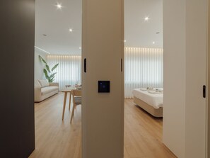 A modern hotel room with a wooden floor, a bed, a seating area with a table and chairs, and a large plant. - Apartment  by Interhome (Porto)