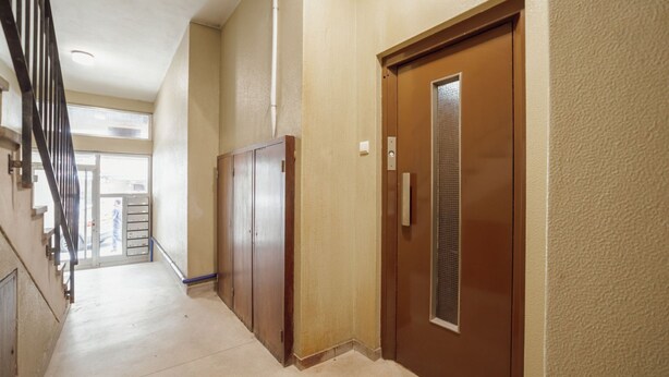 Un pasillo con una puerta de madera y una puerta de ascensor metálica.