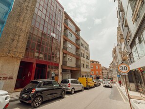 Eine Straße mit parkenden Autos, einem Geschwindigkeitsbegrenzungsschild und mehrstöckigen Gebäuden mit Balkonen.