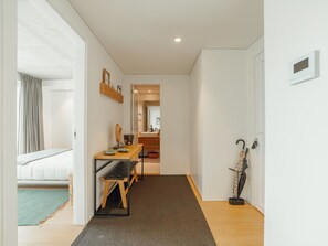 A hallway leading to a bedroom with a bed, a table with a chair, and a coat rack with an umbrella. - BEACH & SUN APARTMENT by VACATIONY by Interhome (Porto)