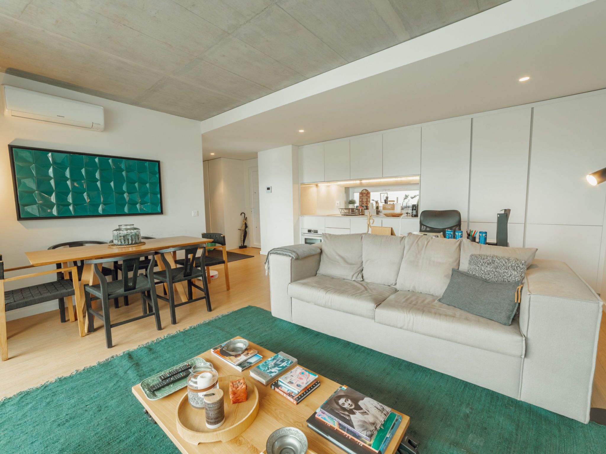 A modern living room with a sofa, coffee table, and a dining area with chairs and a table.