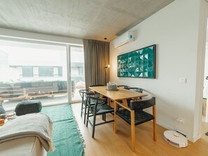 A modern living room with a dining area, large windows, and a view of the outside. - BEACH & SUN APARTMENT by VACATIONY by Interhome (Porto)