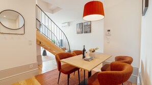 A modern dining area with a wooden table, orange chairs, and a red pendant light. - Apartment  by Interhome (Porto)