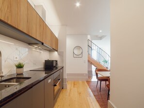 A modern kitchen with a marble countertop, wooden cabinets, and a built-in oven. - Apartment  by Interhome (Porto)