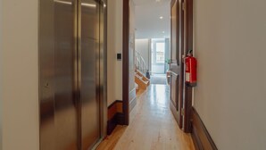 A hallway with a metallic elevator and a wooden door leading to a staircase. - Apartment  by Interhome (Porto)