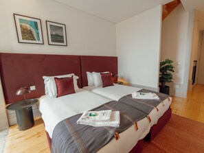 A hotel room with a large bed, two bedside tables, a potted plant, and artwork on the wall. - Apartment  by Interhome (Porto)