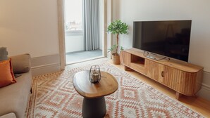 A modern living room with a flat-screen TV, a wooden entertainment unit, a sofa, a coffee table, and a patterned rug. - Apartment  by Interhome (Porto)