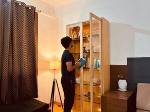 Eine Person steht in einem Raum mit einer gläsernen Vitrine, die Bücher und Dekorationsobjekte beherbergt.