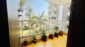 Een balkon met een hekwerk, plantenbakken en uitzicht op een woonwijk met gebouwen en bomen.