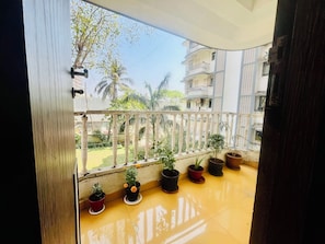 A balcony with a railing, potted plants, and a view of a residential area with buildings and trees. - Peaceful  2BHK in Versova Mumbai with multiple balconies (Mumbai)