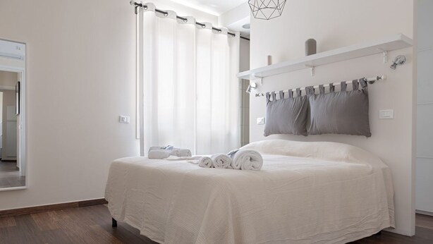 Ein Schlafzimmer mit einem großen Bett, einer Duschvorhang, einem Handtuchhalter und einem Spiegel.