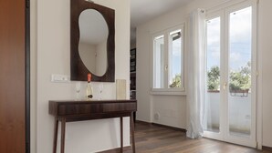 Ein Zimmer mit einem Holzkonsolentisch, einem großen Spiegel und einer Schiebetür, die auf einen Balkon führt.