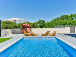 Una piscina amb gandules i zona de barbacoa.