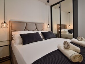 A neatly made bed with pillows, a bedside table, a mirror, and a towel. - Villa La Perla Apt A3 with heated rooftop pool by Interhome (Zadar/Bibinje)