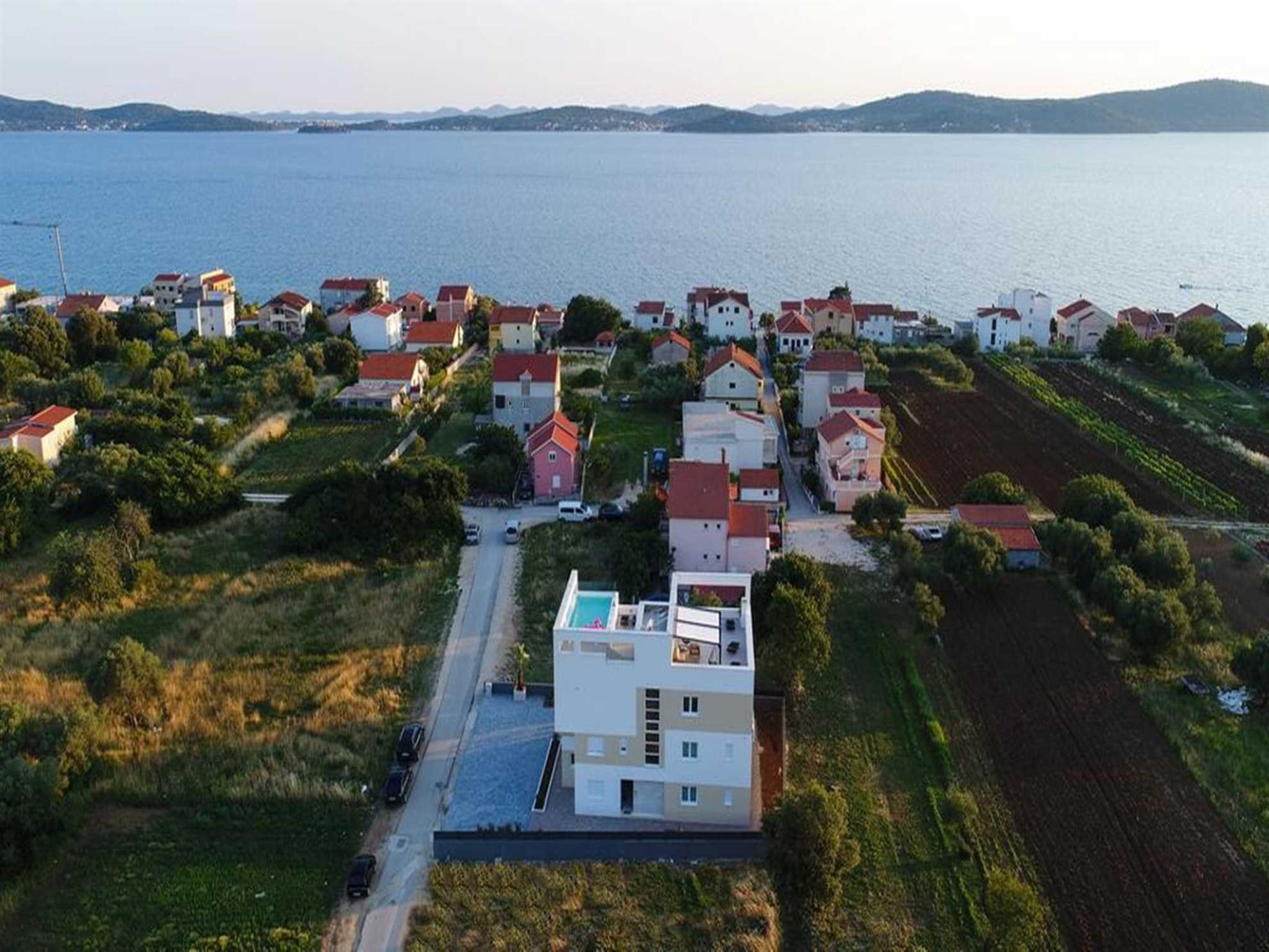 A coastal residential area with houses, a road, and a body of water.