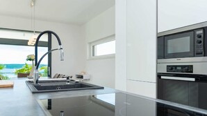 A modern kitchen with a built-in stove, a microwave, and a sink with a faucet. - Vacation home  by Interhome (Rovanjska)
