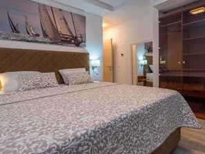 A hotel room with a large bed, a headboard, a painting of sailboats on the wall, and a walk-in closet. - Luxury Villa Michele with infinity pool by Interhome (Rovanjska)