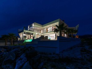 Ein modernes, mehrgeschossiges Haus mit Flachdach, großen Fenstern und einem Swimmingpool.