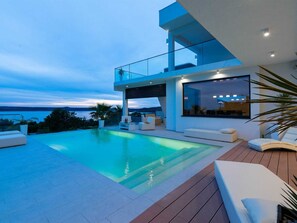 A modern house with a swimming pool, outdoor seating, and a view of the landscape. - Luxury Villa Michele with infinity pool by Interhome (Rovanjska)