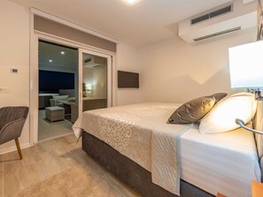 A bedroom with a bed, a chair, a TV, and an air conditioning unit. - Luxury Villa Michele with infinity pool by Interhome (Rovanjska)