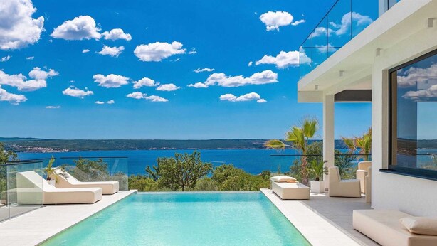 A modern outdoor swimming pool with a clear view of the sea and a distant shoreline. - Vacation home  by Interhome (Rovanjska)