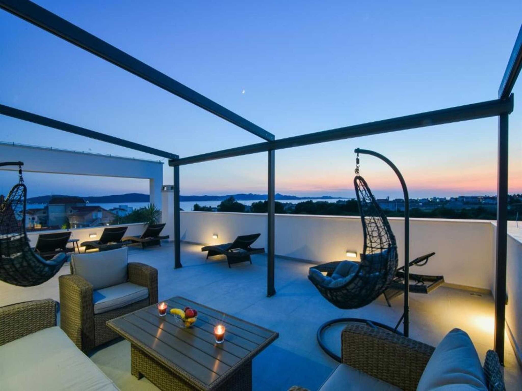 Eine Terrasse im Freien mit Hängestühlen, einem Tisch mit Obst und Blick auf die Landschaft.