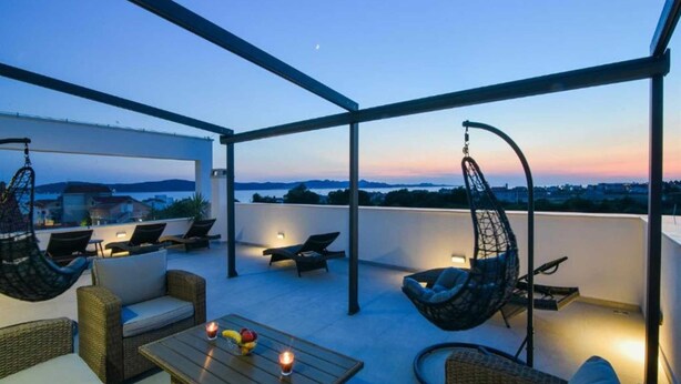 Eine Terrasse im Freien mit Hängestühlen, einem Tisch mit Obst und Blick auf die Landschaft.
