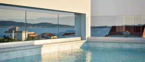 A modern building with a pool and a view of the sea.