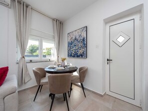 A dining area with a round table, four chairs, a vase with flowers, and a painting on the wall. - Vacation home  by Interhome (Pridraga)