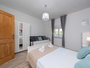 A bedroom with a bed, a wooden wardrobe, a window with curtains, and a chandelier. - Dalmatian Holiday house Marcella with pool by Interhome (Pridraga)