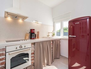A compact kitchen with a gas stove, oven, and a red refrigerator. - Dalmatian Holiday house Marcella with pool by Interhome (Pridraga)